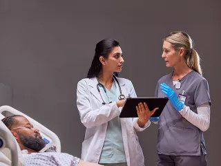 Two healthcare professionals discuss data on a tablet device